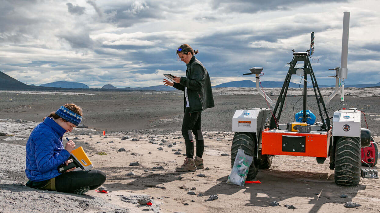 Two scientists take measurements of soil in an empty landscape