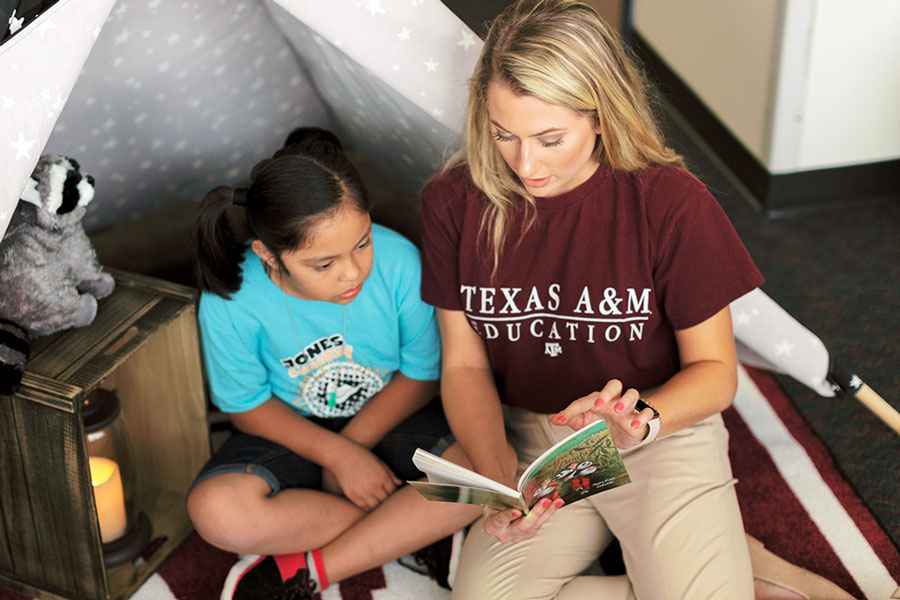 A Texas A&amp;M student reads a book to a child